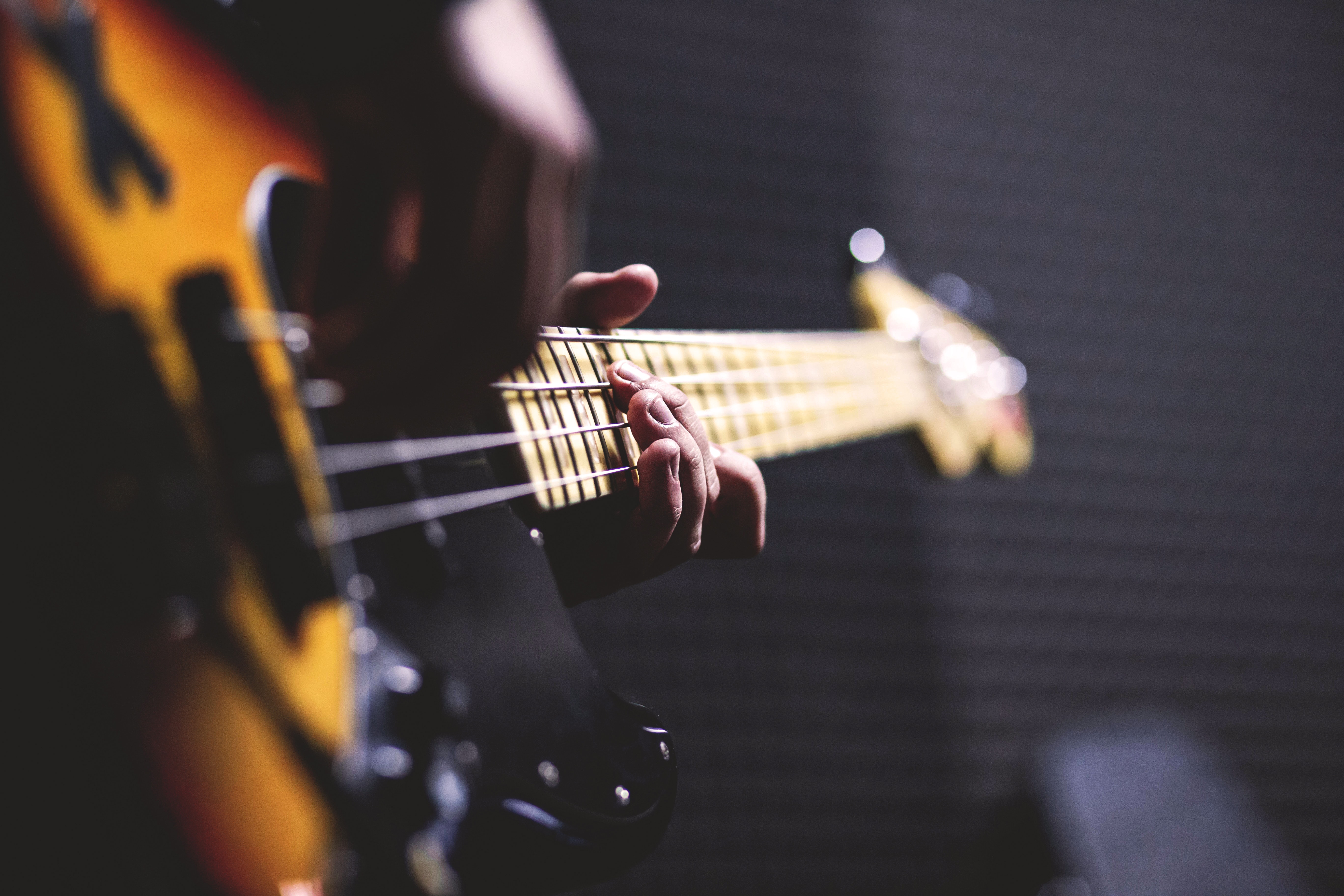 Person Playing Sun Burst Electric Bass Guitar in Bokeh Photography by freestock.org